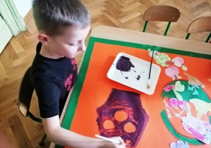 chłopiec maluje farbami bakłażana